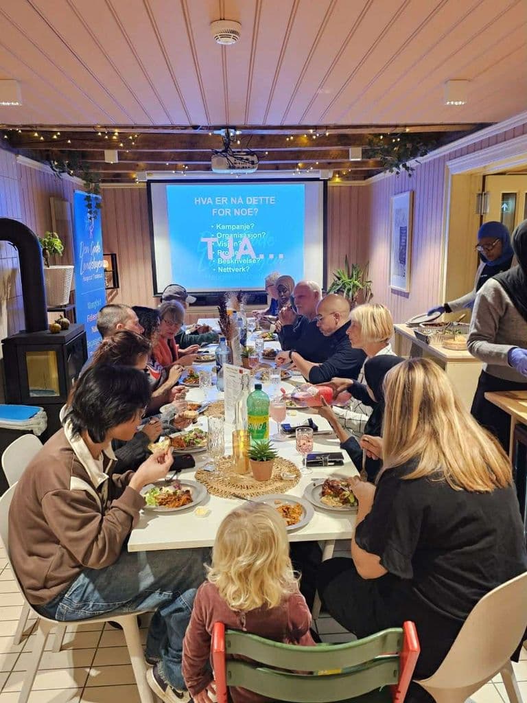 Folk rundt et langbord med mat under et dialogmøte