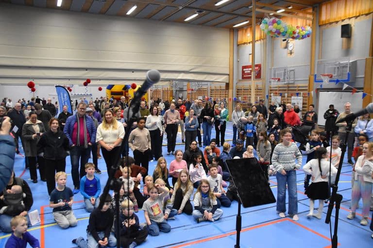 Stort publikum av barn og voksne foran scenen i hallen