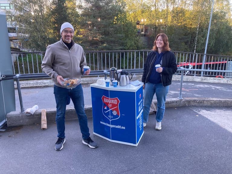 To frivillige med kaffe og boller ved en stand på brua